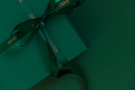 green gift box with a sating ribbon and DUINE in gold on it